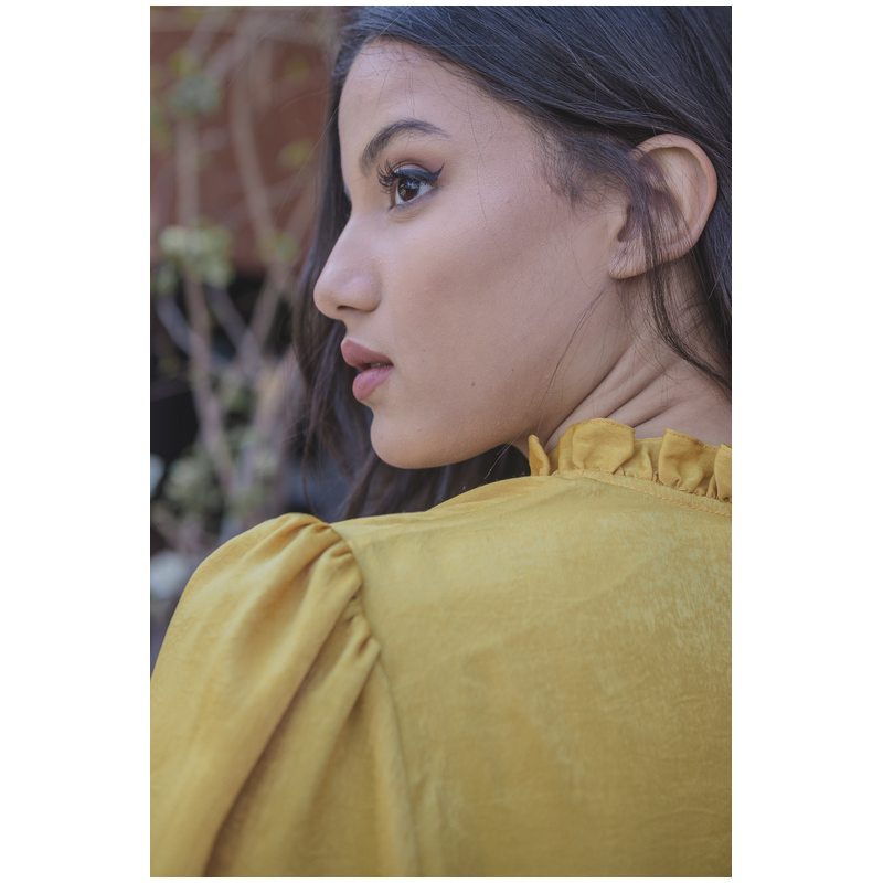 Détails de la blouse jaune : boutons dorés et tissu fluide