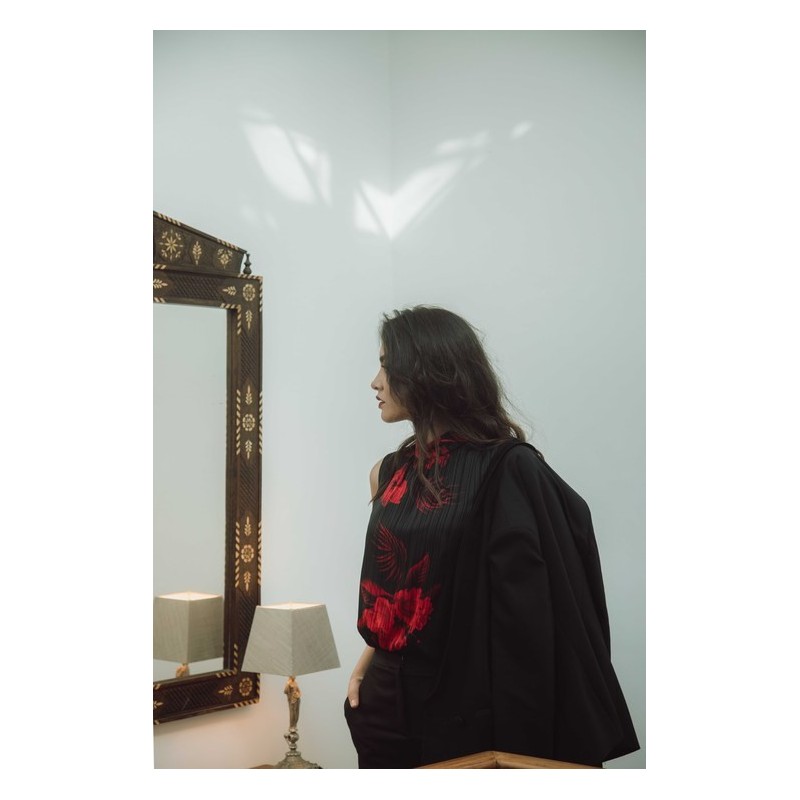 Blouse élégante avec des motifs rouges sur fond noir.