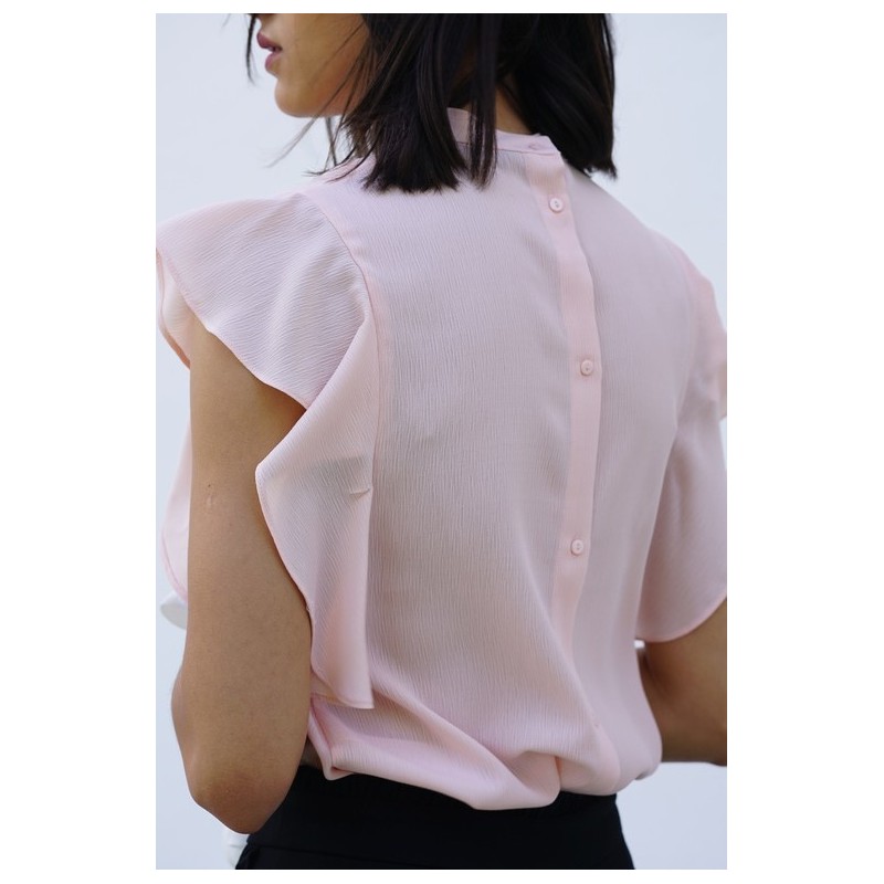Détails du dos de la blouse rose clair à manches à volants.