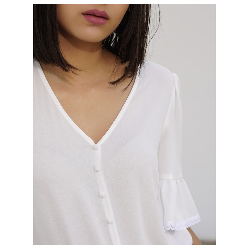 Le devant de la blouse de couleur blanche avec des manches en cloche