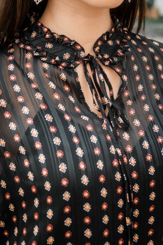 Le devant d'une blouse noire élégante avec des motifs.