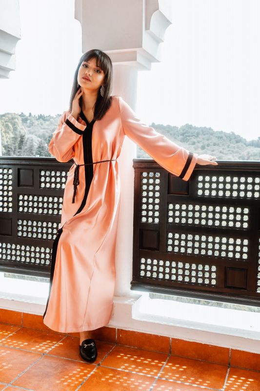 Caftan abricot avec une ceinture noire pour une élégance estivale.