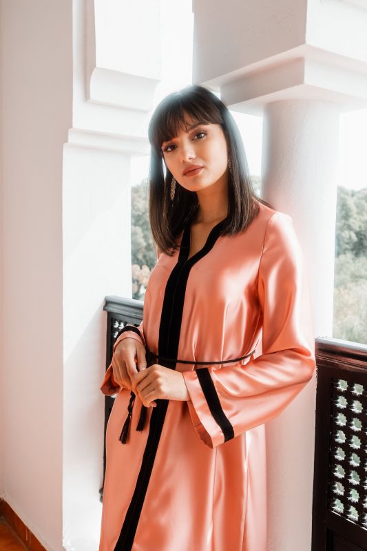 Caftan abricot associé à une ceinture noire pour une tenue estivale et chic.