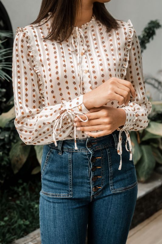 Explorez les finitions dorées de cette chemise blanche pour une tenue unique.