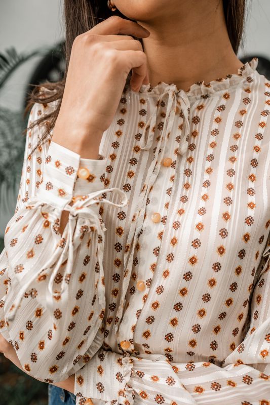 Explorez les finitions dorées de cette chemise blanche pour une tenue unique.