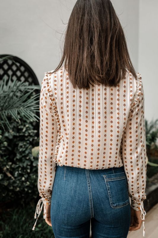 Explorez les finitions dorées de cette chemise blanche pour une tenue unique.