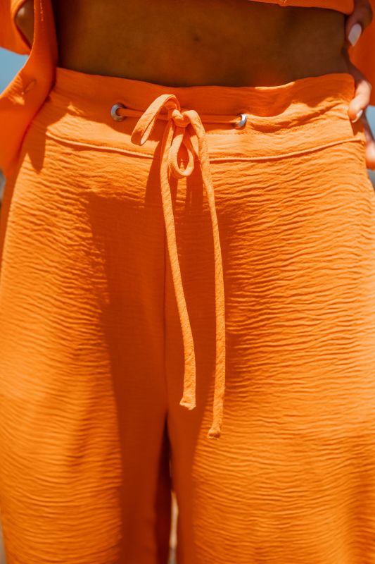 Détails en gros plan du pantalon long orange pour femmes.