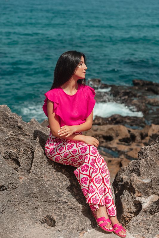 Un élégant pantalon rose orné, pour une tenue remarquable sur fond blanc.