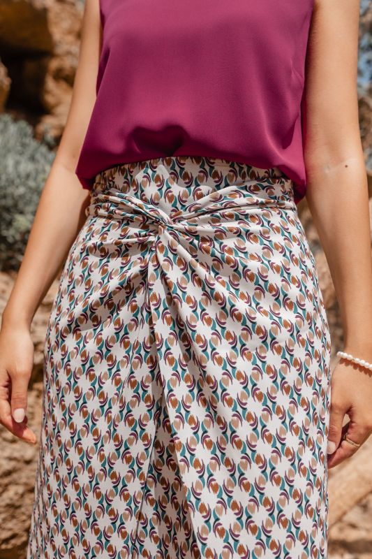 Détails de la jupe : Fond blanc avec des motifs colorés pour une tenue festive.