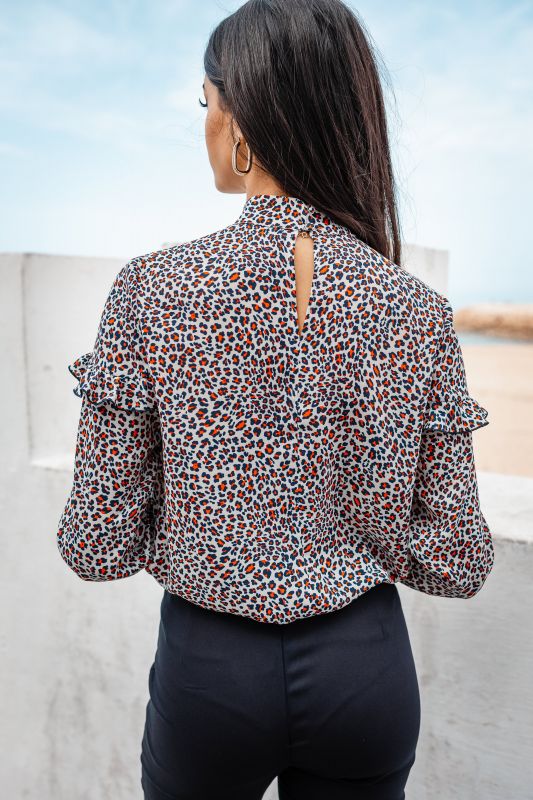 Blouse pour femme ornée de détails raffinés sur un fond neutre.