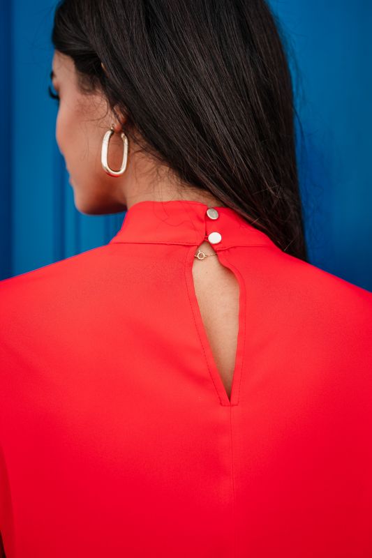 Détails de la blouse rouge pour femme, révélant sa teinte profonde et ses finitions soignées.