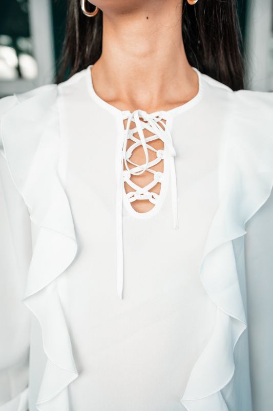Blouse blanche pure pour femme sur un fond neutre.