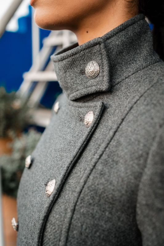 Détails de la doublure boutonnée d'un manteau gris.