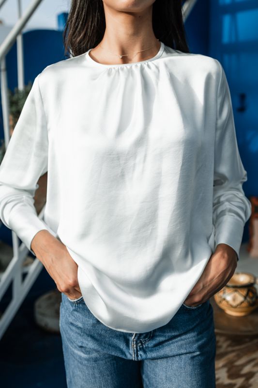 Blouse blanche intemporelle pour femme sur un fond neutre.