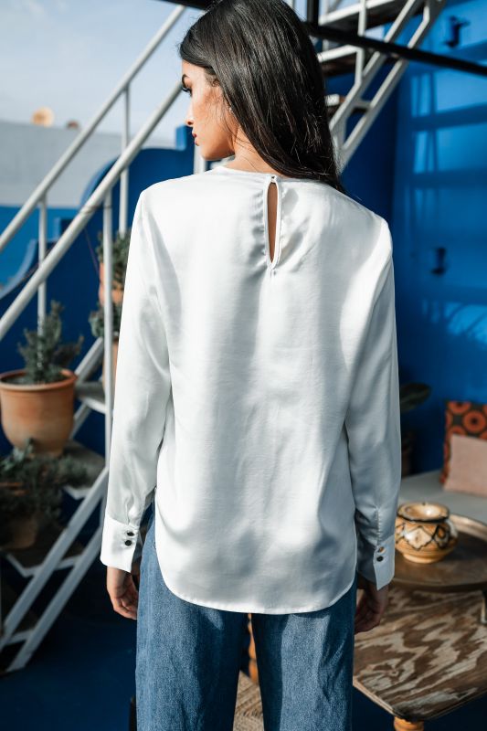 Détails de la blouse blanche pour femme montrant sa simplicité élégante.