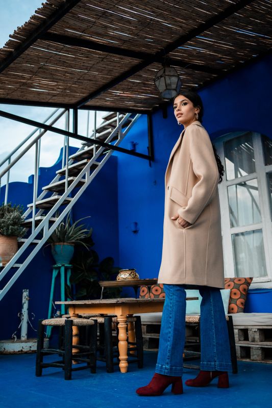 Manteau de couleur beige, rehaussé par un bouton discret.