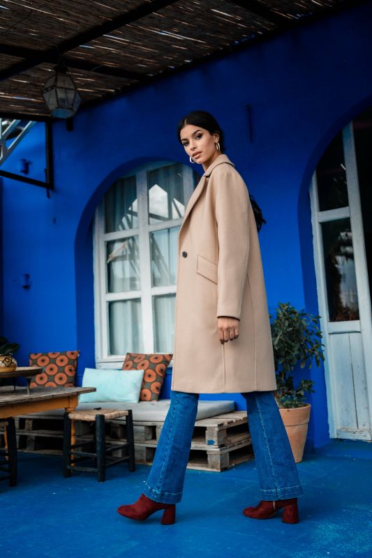 Un manteau beige agrémenté d'un bouton, une touche de style subtile.