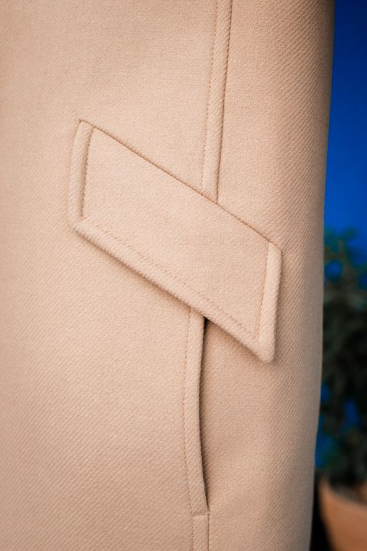 Détails du manteau beige avec un bouton unique.