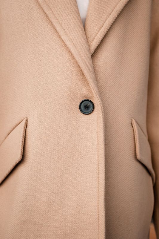 Détails du manteau beige avec un bouton unique.