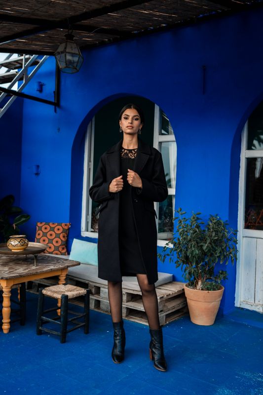 Un manteau noir orné d'un seul bouton, ajoutant une touche de style subtile.
