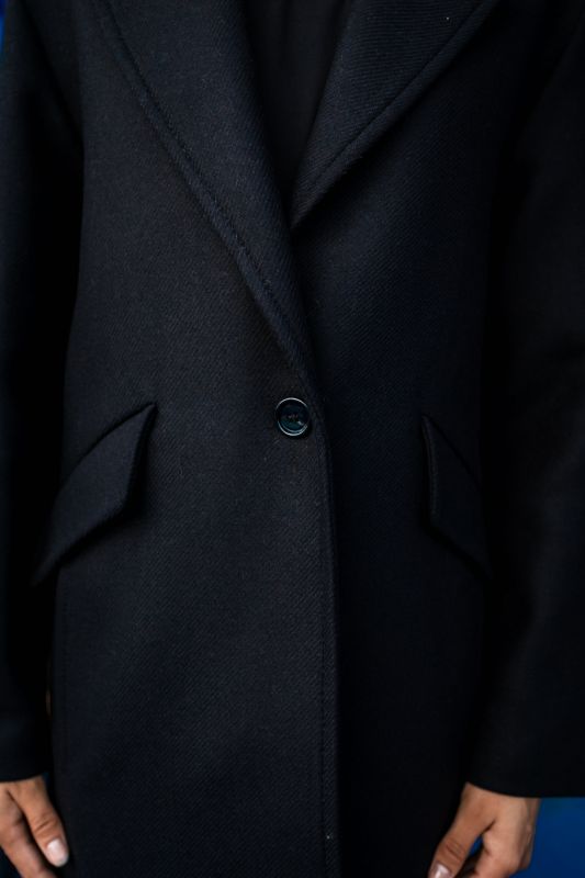 Détails du manteau noir avec un bouton solitaire.
