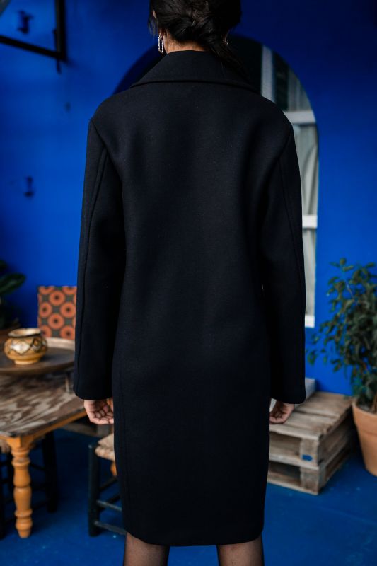 Détails du manteau noir avec un bouton solitaire.