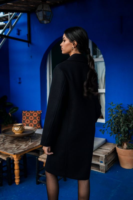 Détails du manteau noir avec un bouton solitaire.