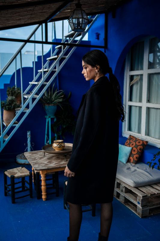 Manteau noir avec un bouton discret, élégance subtile.