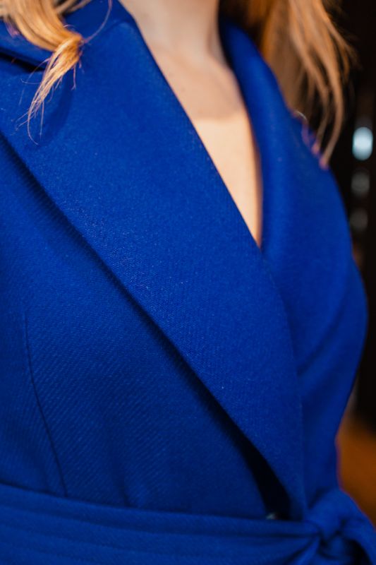 Détails du manteau bleu avec une ceinture bleue, une harmonie de couleur.