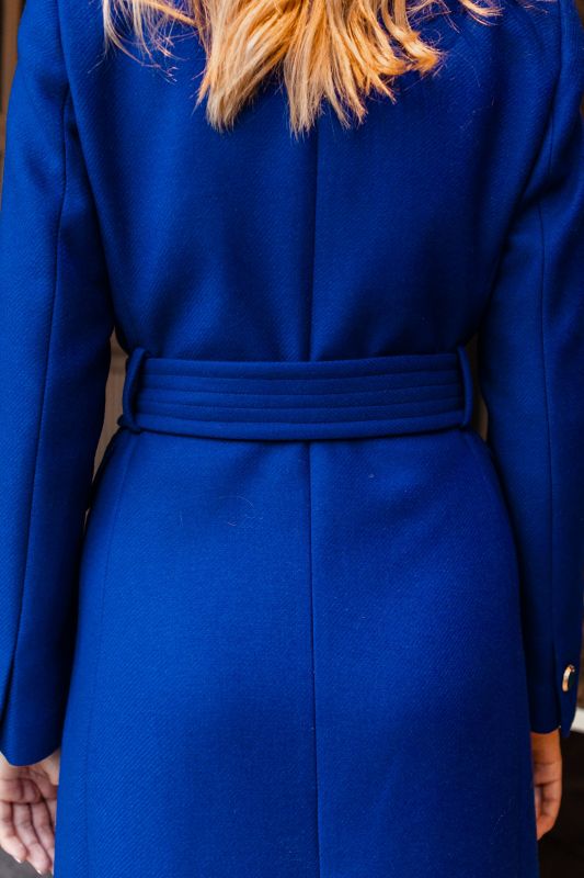Détails du manteau bleu avec une ceinture bleue, une harmonie de couleur.