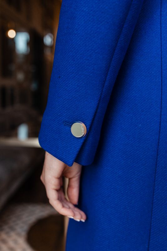Détails du manteau bleu avec une ceinture bleue, une harmonie de couleur.