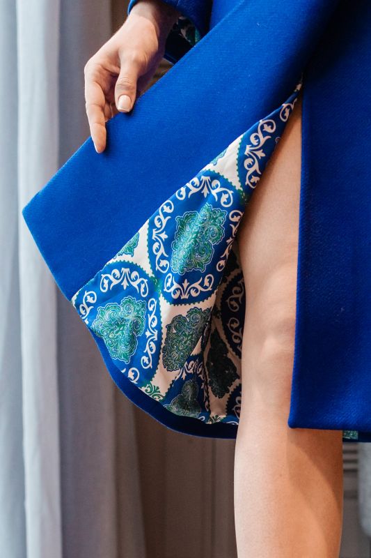 Détails du manteau bleu avec une ceinture bleue, une harmonie de couleur.