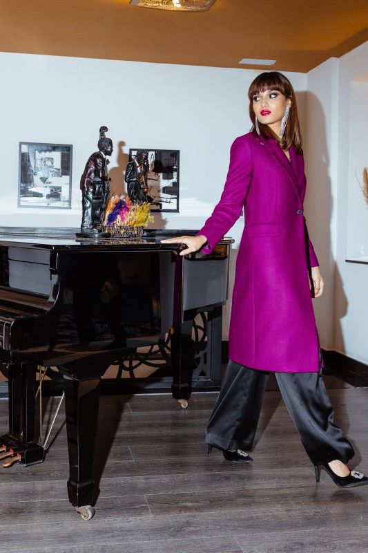 Manteau de couleur framboise, une teinte vive accentuée par un bouton.
