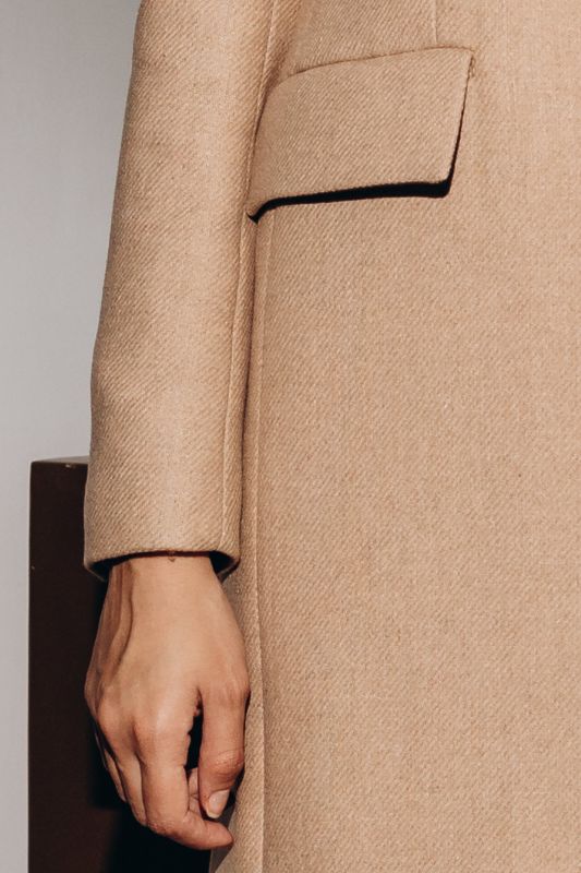 Détails du manteau blanc cassé à deux boutons, une pièce raffinée.