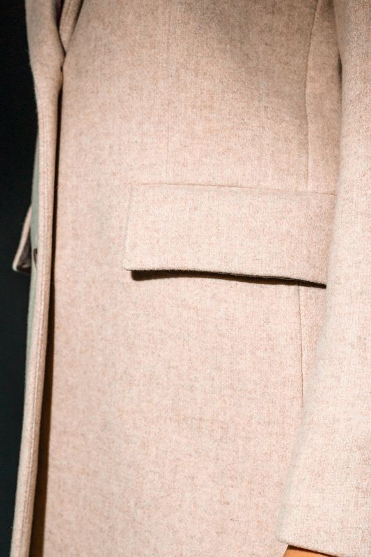 Détails du manteau beige à deux boutons, une touche classique.