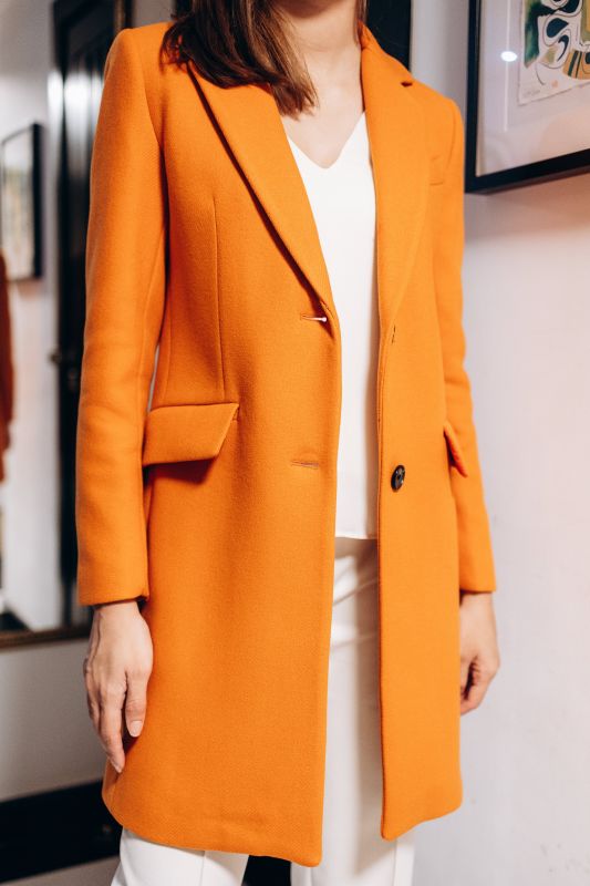 Détails du manteau orange à deux boutons, une touche audacieuse.