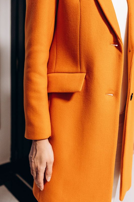 Détails du manteau orange à deux boutons, une touche audacieuse.