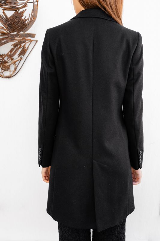 Détails du manteau noir à deux boutons, une touche classique.