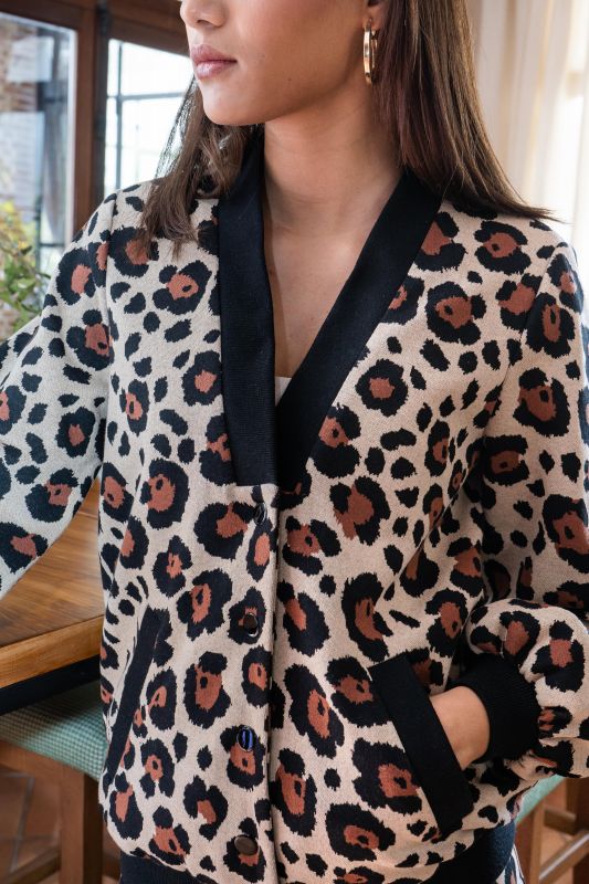 Détails du bomber : Motifs noirs et marron sur fond blanc cassé.