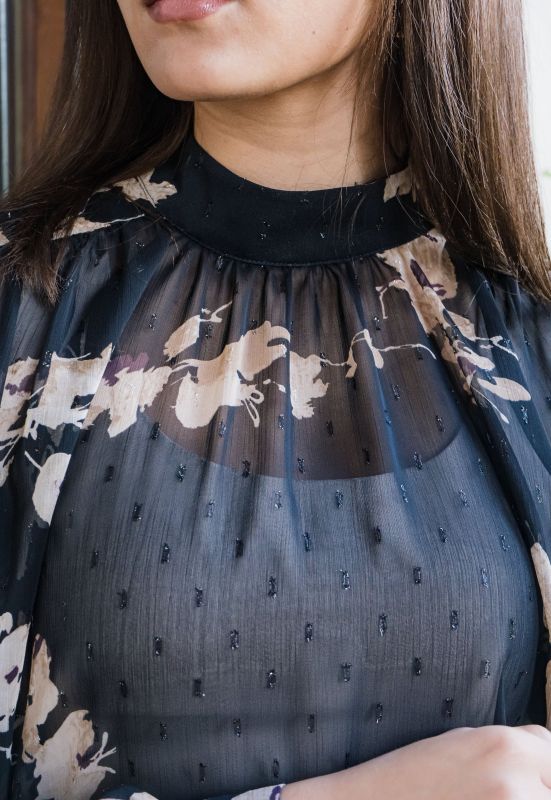Détails de la blouse imprimée pour femme, mettant en évidence son motif en noir et beige et ses finitions soignées.
