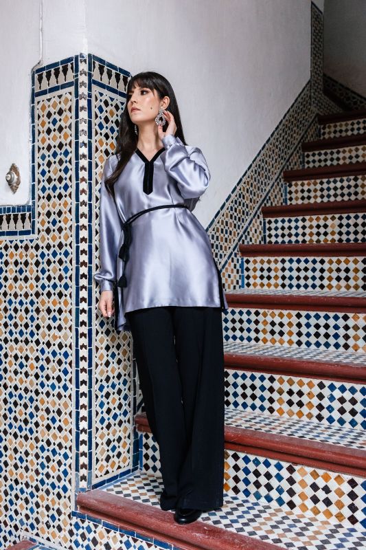 Blouse grise sobre pour femme sur un fond neutre.