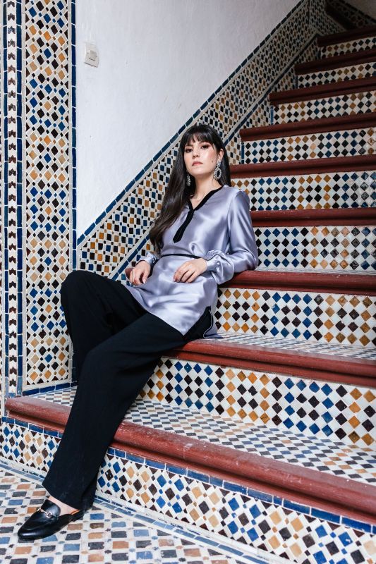 Blouse grise sobre pour femme sur un fond neutre.