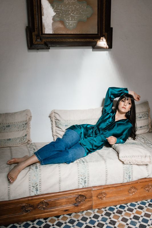 Blouse pour femme en vert foncé sur un fond neutre.