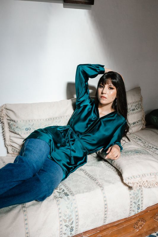 Blouse pour femme en vert foncé sur un fond neutre.