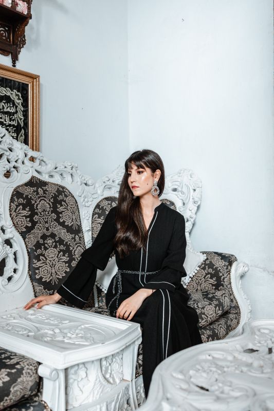 Caftan noir avec une ceinture blanche pour un contraste élégant.