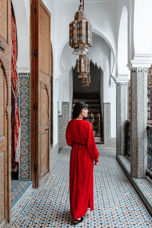 Robe traditionnelle en rouge, rehaussée d'une ceinture noire.