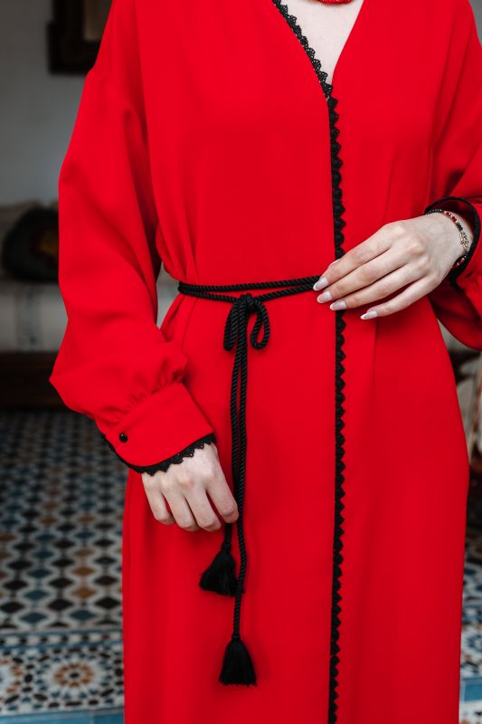 Caftan rouge en détail : une ceinture noire élégante, des broderies fines et une coupe impeccable.