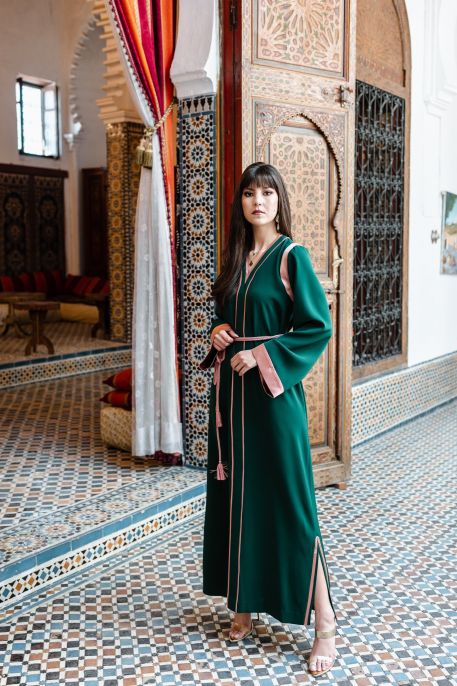 Caftan vert avec une ceinture rose pour une touche de couleur vive.