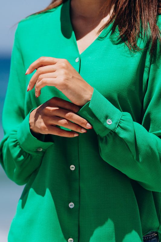 Blouse verte vibrante pour femme sur un fond neutre.