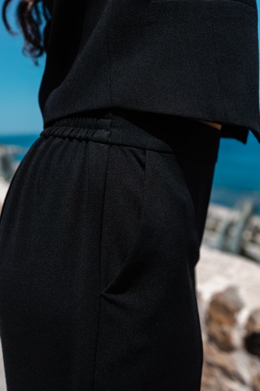 Détails du pantalon noir, une pièce polyvalente et élégante.